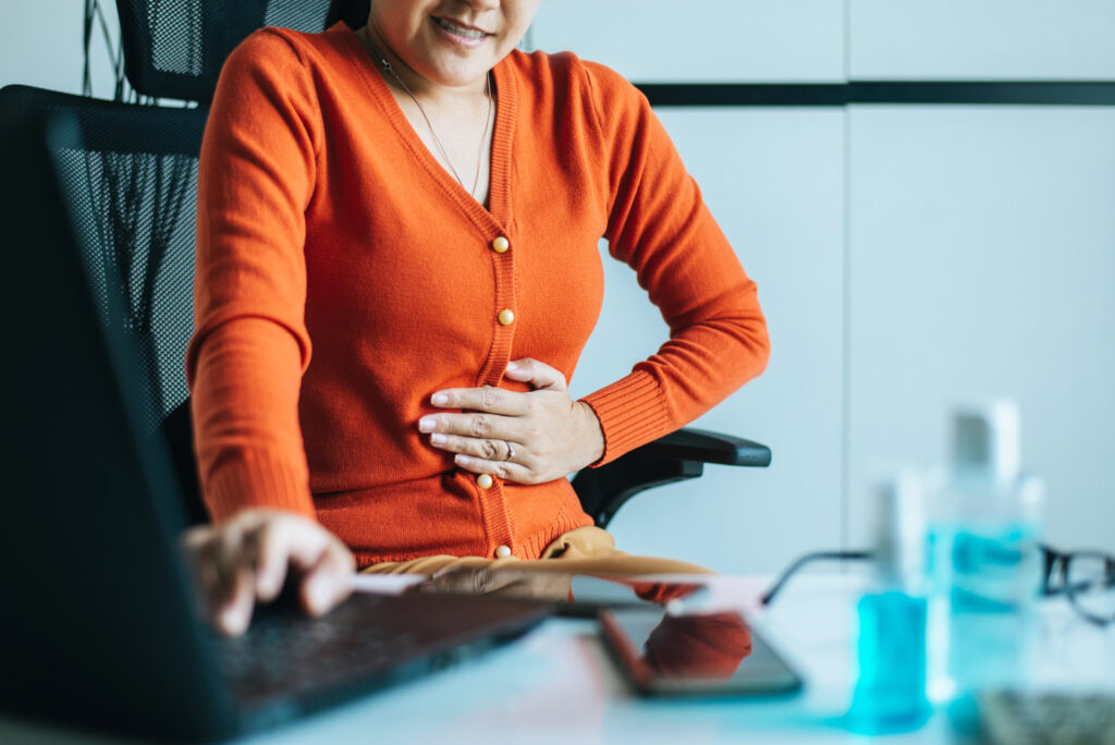 An image of a women experiencing abdominal pain from SIBO which is caused by adhesions.